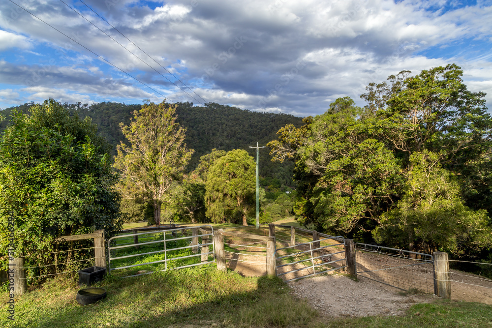 Rural property in Australia, gate leads to dirt tracks and woodlands large tree covered hill in the distance Rural property in Australia, gate leads to dirt tracks and woodlands large tree covered hill in the distance