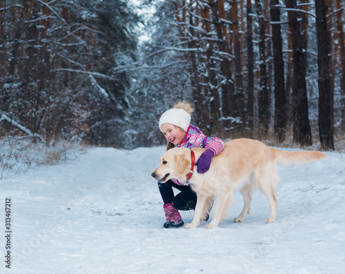 girl having fun with her dog golden retriever in a winter day.