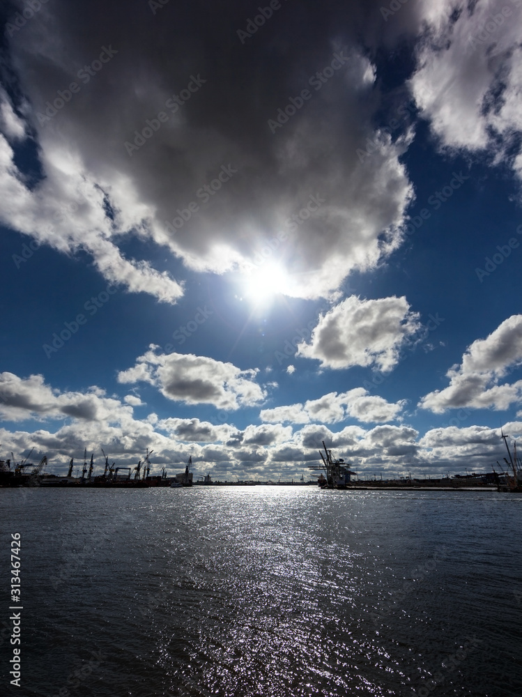 Sun behind dramatic clouds over Elbe river in Hamburg, Germany