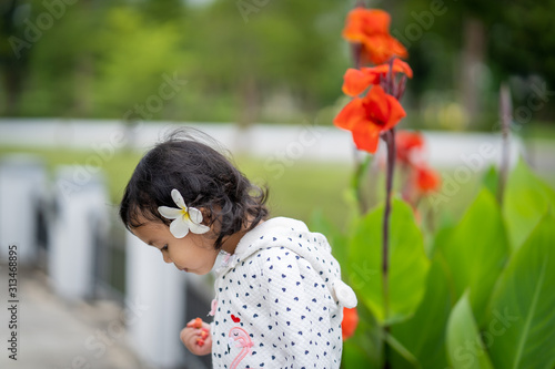 Cute little girl playing in park with plumeria flower on her ear.