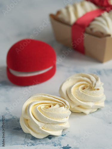 Homemade marshmallows (zephyr) on the table. Closeup, selective focus on marshmallows. Homemade sweets. Vertical orientation. Red casket for a ring or gift in the background.