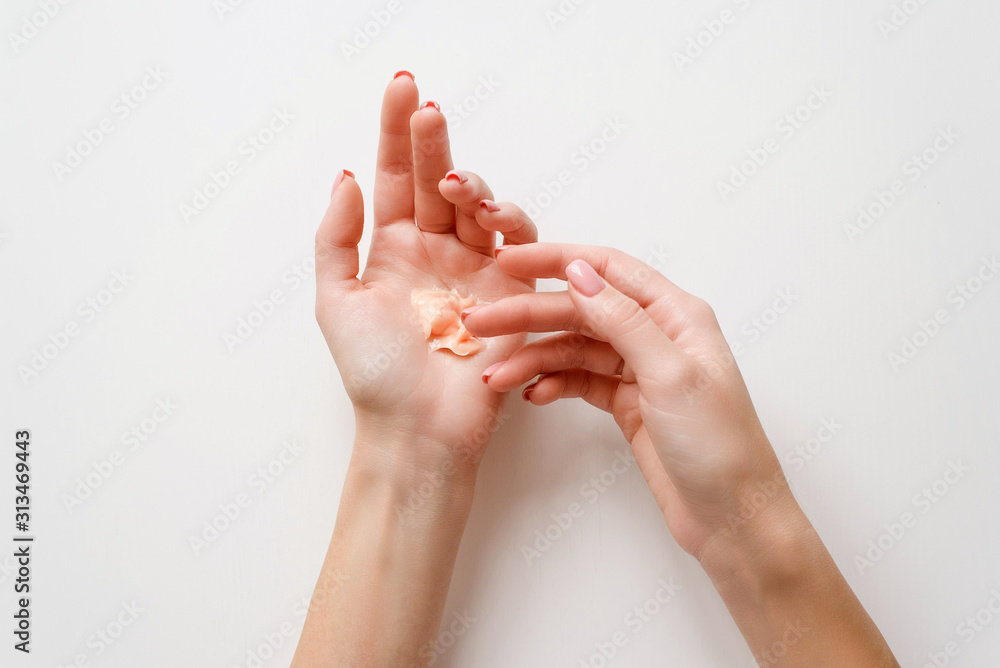 The girl distributes moisturizing cream on her hands. Hands on a white background with a jar of white cream. Flat lay top view minimalism style. Beauty concept, dermatology cosmetic The girl distributes moisturizing cream on her hands. Hands on a white background with a jar of white cream. Flat lay top view minimalism style. Beauty concept, dermatology cosmetic
