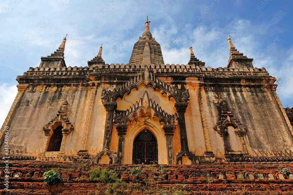 Blue sky above a temple surrounded by green vegetation in old Bagan, Myanmar.