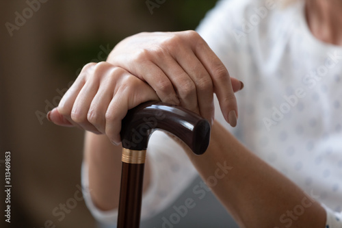 Close up of disabled senior woman hold walking cane