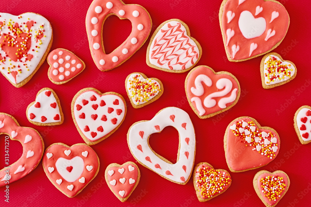 Background of decorated with icing and glazed heart shape cookies on the red background, flat lay. Valentines Day food concept - obrazy, fototapety, plakaty 