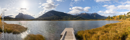 panorama of a footbridge leading into a lake embedded in an autumn mountain and forest frame