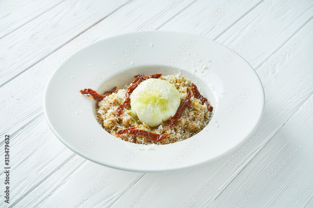 Breakfast with poached eggs, oatmeal and sun-dried tomatoes in a ceramic bowl on a white wooden background. Close up. Copy space Breakfast with poached eggs, oatmeal and sun-dried tomatoes in a ceramic bowl on a white wooden background. Close up. Copy space
