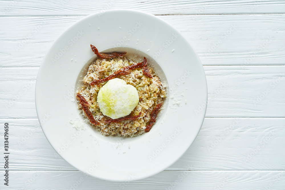 Breakfast with poached eggs, oatmeal and sun-dried tomatoes in a ceramic bowl on a white wooden background. Close up. Copy space