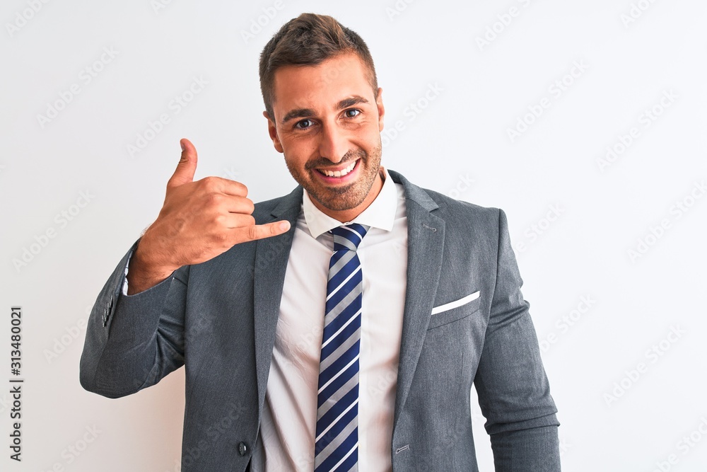 Young handsome business man wearing suit and tie over isolated background smiling doing phone gesture with hand and fingers like talking on the telephone. Communicating concepts. Young handsome business man wearing suit and tie over isolated background smiling doing phone gesture with hand and fingers like talking on the telephone. Communicating concepts.