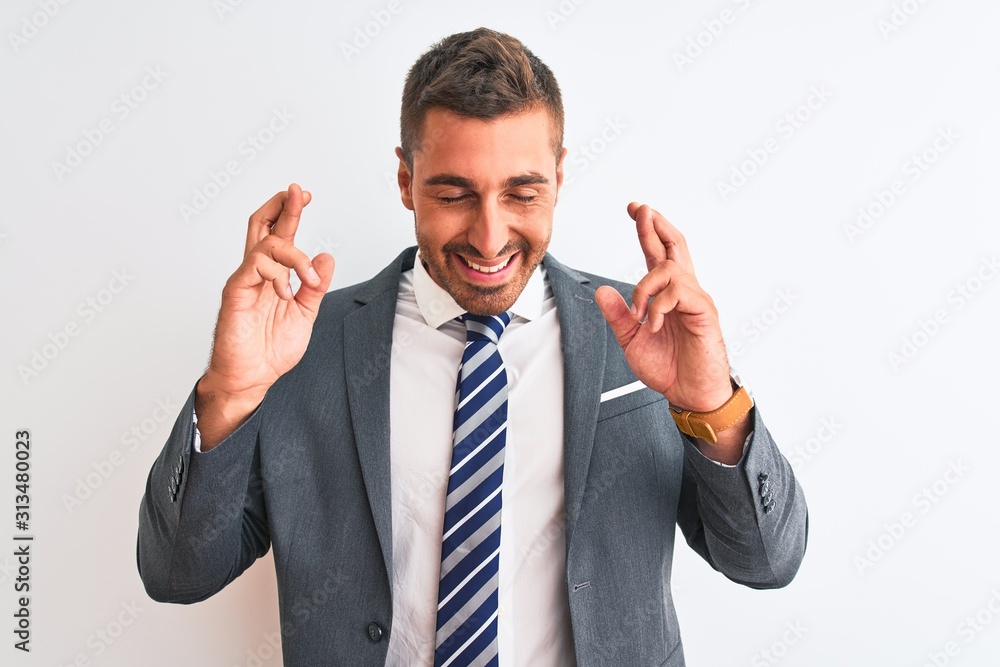 Young handsome business man wearing suit and tie over isolated background gesturing finger crossed smiling with hope and eyes closed. Luck and superstitious concept. Young handsome business man wearing suit and tie over isolated background gesturing finger crossed smiling with hope and eyes closed. Luck and superstitious concept.