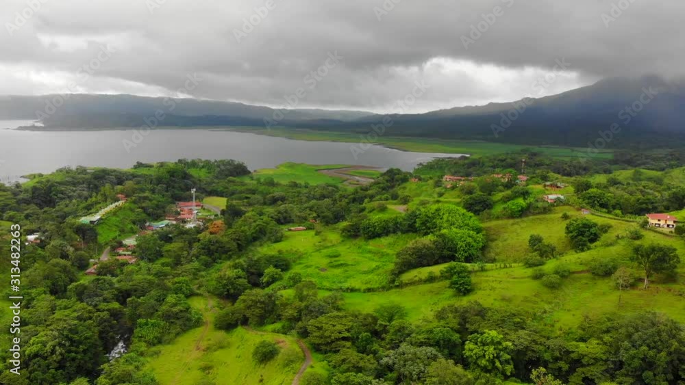Aerial shot, flying backwards, of El Castillo village near Arenal, Costa Rica. Shot of local houses and surroundings, with Arenal lake and volcano in the background. Aerial shot, flying backwards, of El Castillo village near Arenal, Costa Rica. Shot of local houses and surroundings, with Arenal lake and volcano in the background.