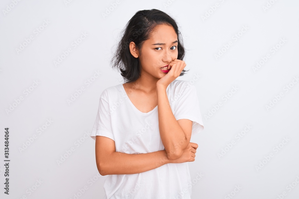 Young chinese woman wearing casual t-shirt standing over isolated white background looking stressed and nervous with hands on mouth biting nails. Anxiety problem. Young chinese woman wearing casual t-shirt standing over isolated white background looking stressed and nervous with hands on mouth biting nails. Anxiety problem.