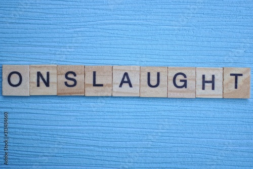 Photography gray word onslaught from small wooden letters on a blue table