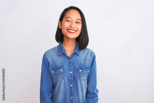 Fotografie Young beautiful chinese woman wearing denim shirt standing over isolated white background with a happy and cool smile on face