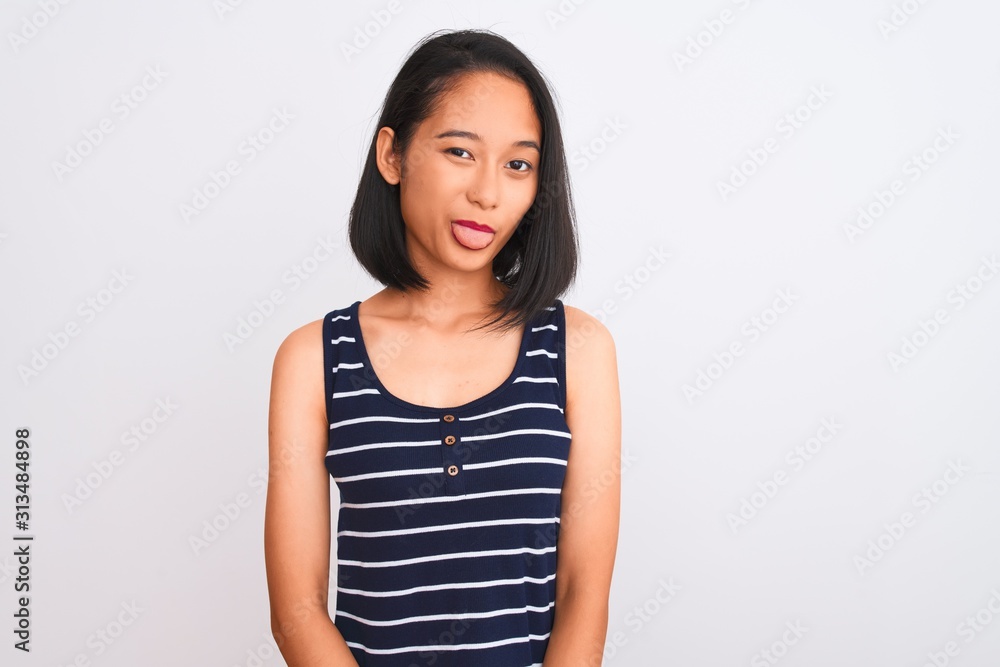 Young chinese woman wearing striped t-shirt standing over isolated white background sticking tongue out happy with funny expression. Emotion concept. Young chinese woman wearing striped t-shirt standing over isolated white background sticking tongue out happy with funny expression. Emotion concept.