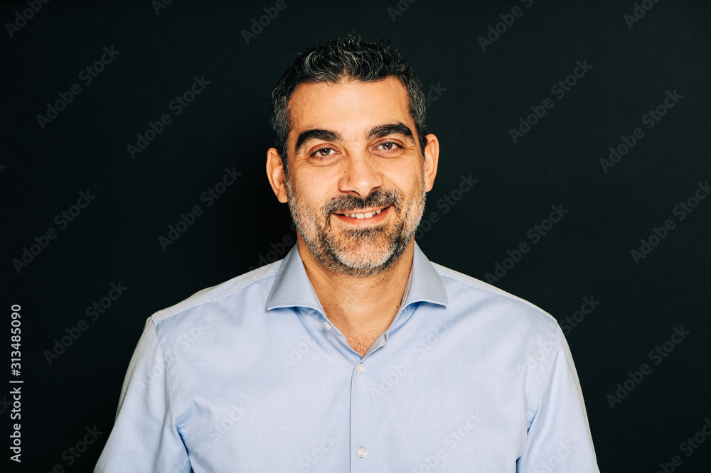 Obraz premium Studio portrait of handsome man wearing formal blue shirt, posing on black background