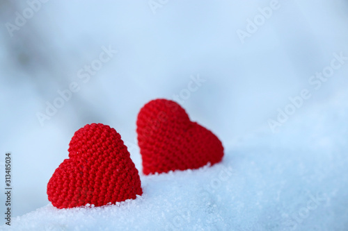 Valentine s hearts  greeting card  two red knitted symbols of love in the snow. Background for romantic event  celebration or winter weather