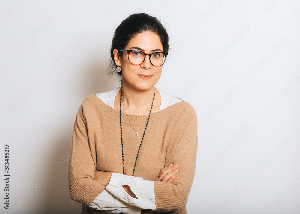 Studio portrait of beautiful brunette woman, wearing glasses, arms crossed, posing on white background - obrazy, fototapety, plakaty 