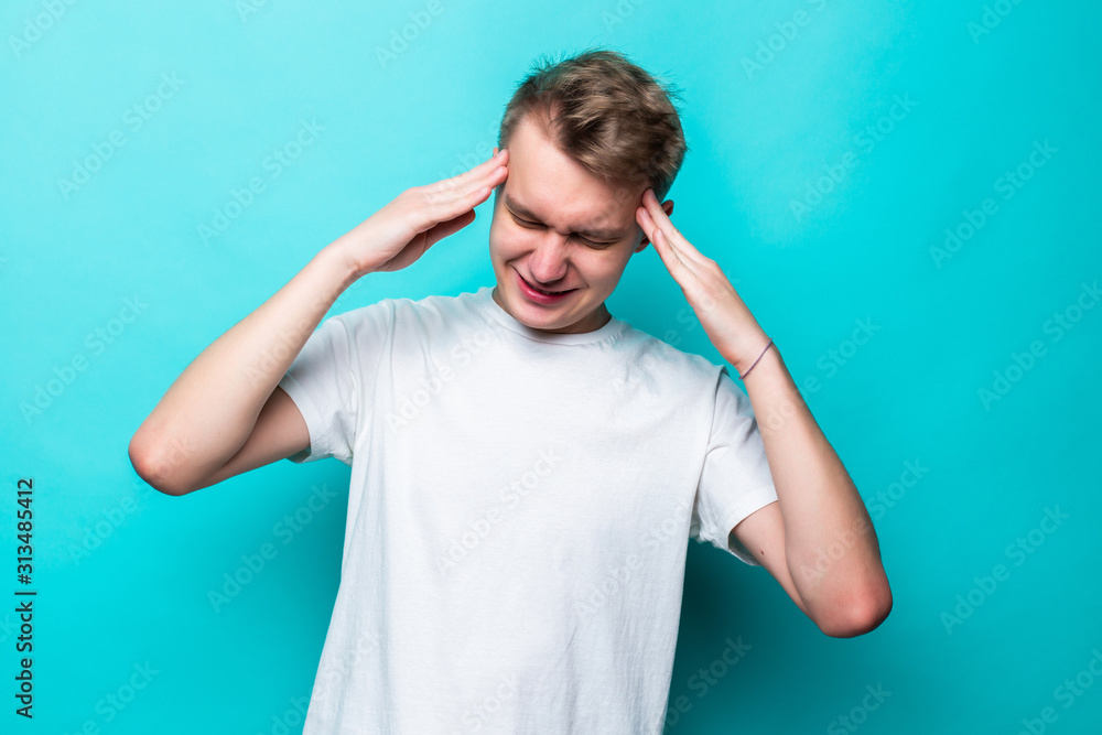 Portrait of young teen man having awful headache while standing over green background. Portrait of young teen man having awful headache while standing over green background.