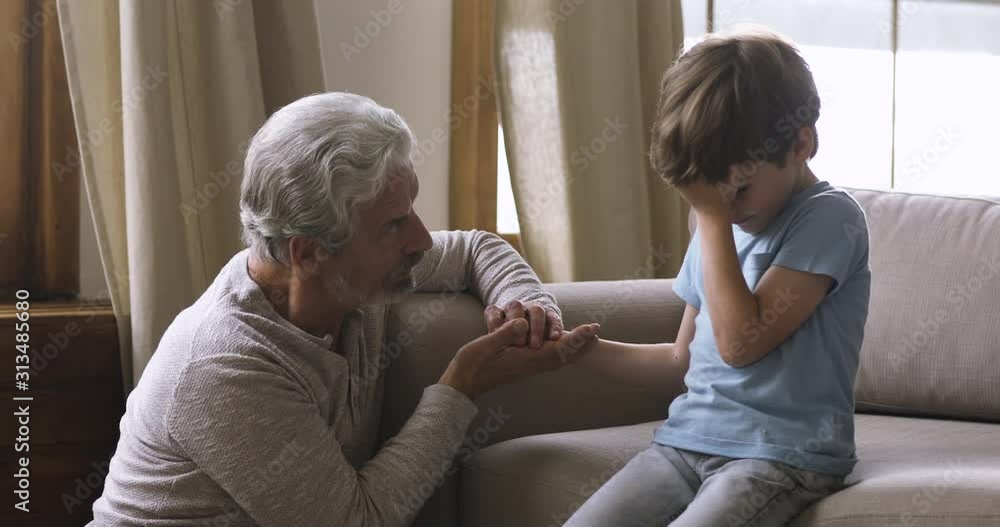 Loving worried old grandpa comforting sad crying little grandson Loving worried old grandpa comforting sad crying little grandson