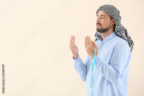 Muslim man praying against light background photo