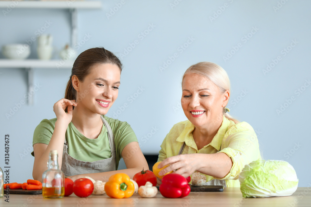 Mature woman and her adult daughter cooking together in kitchen