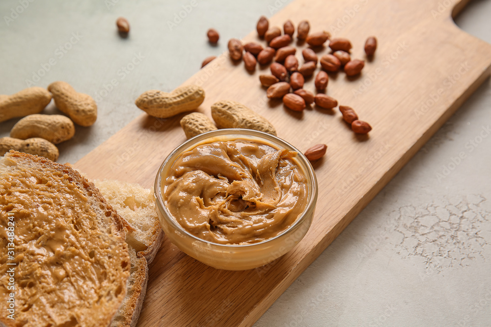 Board with fresh bread and tasty peanut butter on white background Board with fresh bread and tasty peanut butter on white background