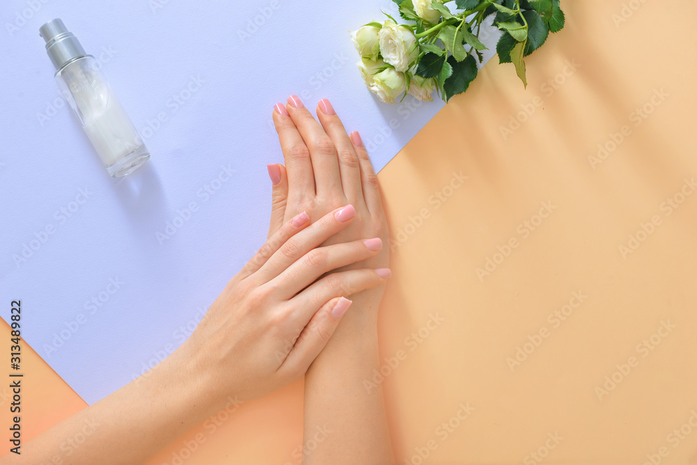 Hands of young woman and bottle of cream with flowers on color background - obrazy, fototapety, plakaty 