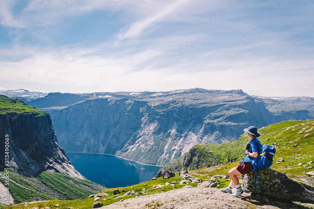 Fototapeta premium Traveling Lifestyle adventure vacations in Norway aerial view landscape. Hike In Norway. Amazing nature view on the way to Trolltunga. Traveller Standing On Famous Norwegian Natural Sight Trolltunga