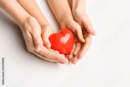 Fototapeta Naklejka Na Ścianę i Meble -  Hands of child and adult with red heart on white background. Cardiology concept