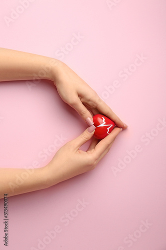 Female hands with red heart on color background. Cardiology concept