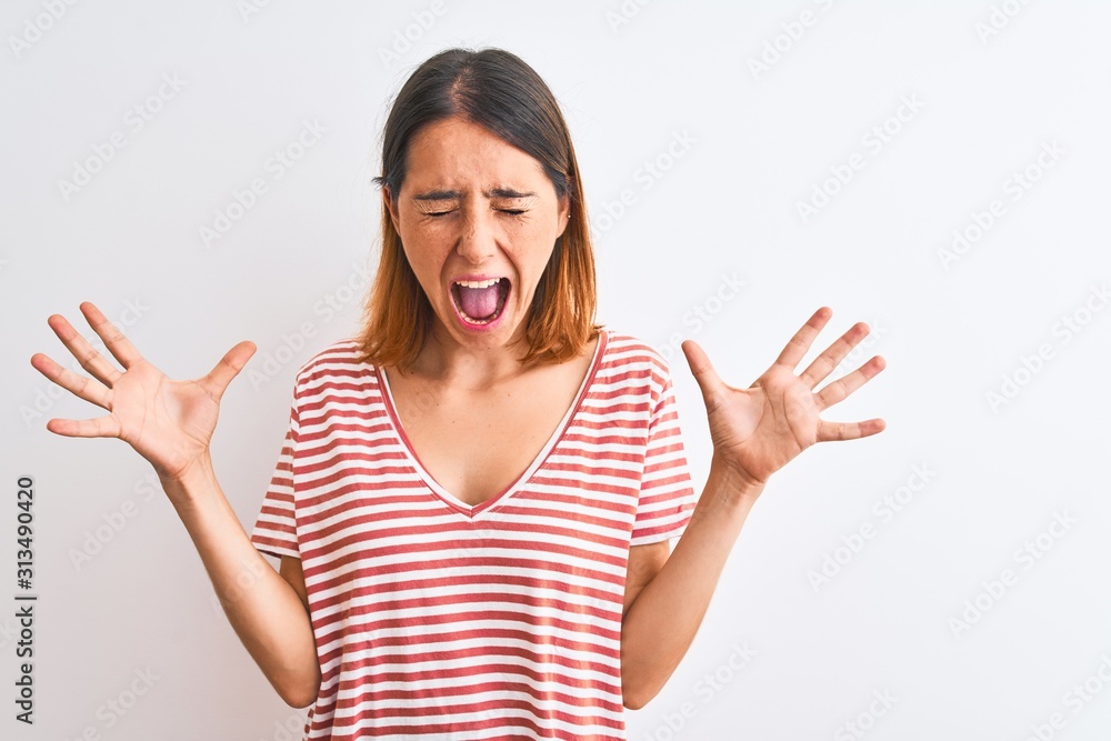 Beautiful redhead woman wearing casual striped red t-shirt over isolated background celebrating mad and crazy for success with arms raised and closed eyes screaming excited. Winner concept Beautiful redhead woman wearing casual striped red t-shirt over isolated background celebrating mad and crazy for success with arms raised and closed eyes screaming excited. Winner concept
