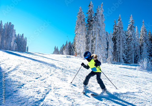 Young boy learning how to ski on slope in mountains during winter vacation