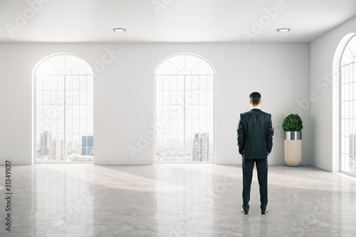 Businessman standing in gallery interior with big window