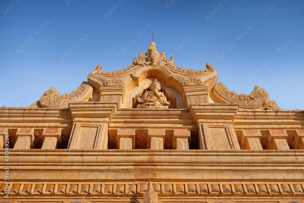 Blue sky above an ancient temple carved with religious motifs in old Bagan, Myanmar.