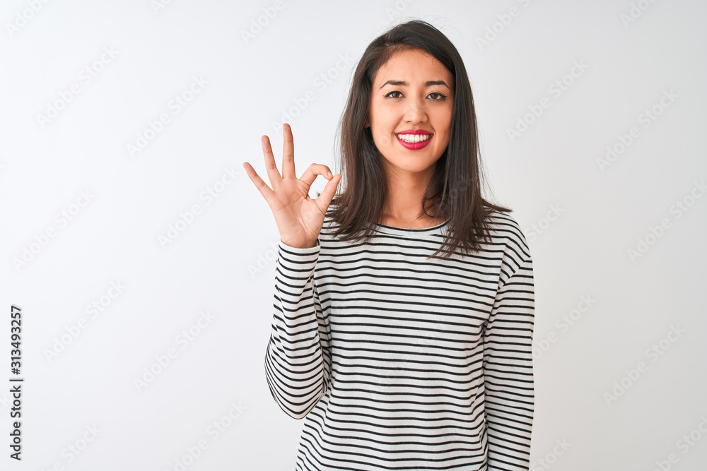 Young beautiful chinese woman wearing striped t-shirt standing over isolated white background smiling positive doing ok sign with hand and fingers. Successful expression. Young beautiful chinese woman wearing striped t-shirt standing over isolated white background smiling positive doing ok sign with hand and fingers. Successful expression.