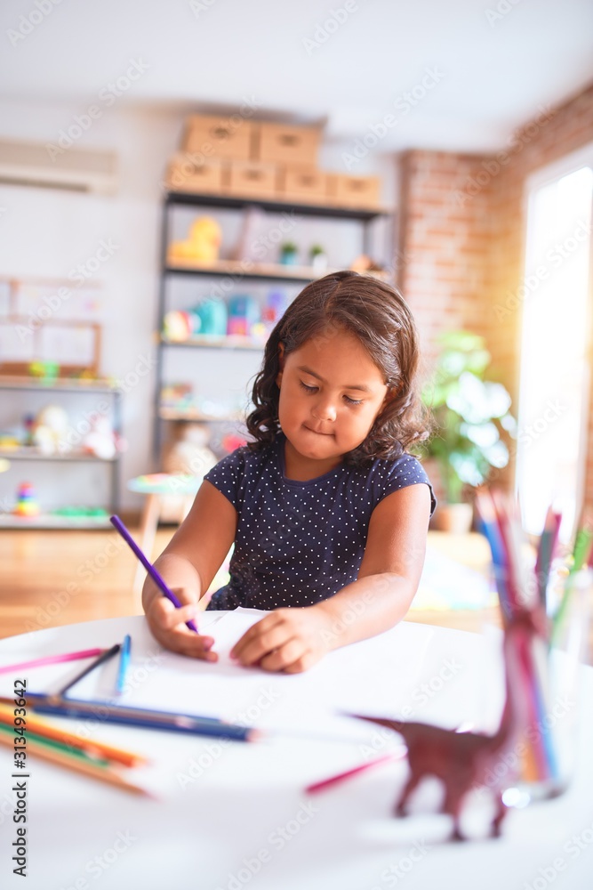 Beautiful toddler girl drawing cute draw using colored pencils at kindergarten Beautiful toddler girl drawing cute draw using colored pencils at kindergarten