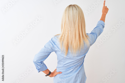 Middle age businesswoman wearing elegant shirt and glasses over isolated white background Posing backwards pointing ahead with finger hand