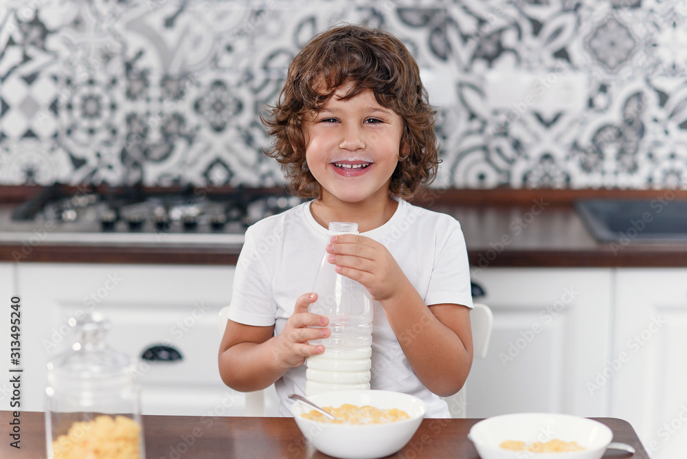 Happy boy feels happiness while eating healthy breakfast of cornflakes and milk at the kitchen. Happy boy feels happiness while eating healthy breakfast of cornflakes and milk at the kitchen.