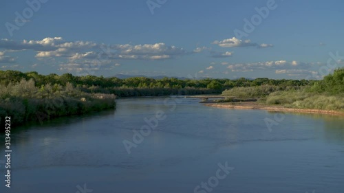 Stunning zoom out of Rio Grande river at dusk with desert mountains in background with cobalt blue skies and emerald green flora along river bank photo
