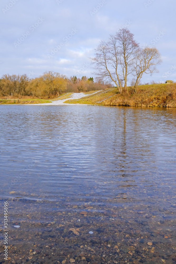 Landscape. Trees, dry grass and a country road along the banks of a small river in late autumn. Landscape. Trees, dry grass and a country road along the banks of a small river in late autumn.