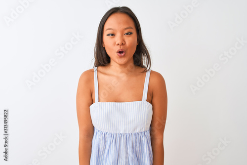 Young chinese woman wearing casual striped dress standing over isolated white background afraid and shocked with surprise expression, fear and excited face.