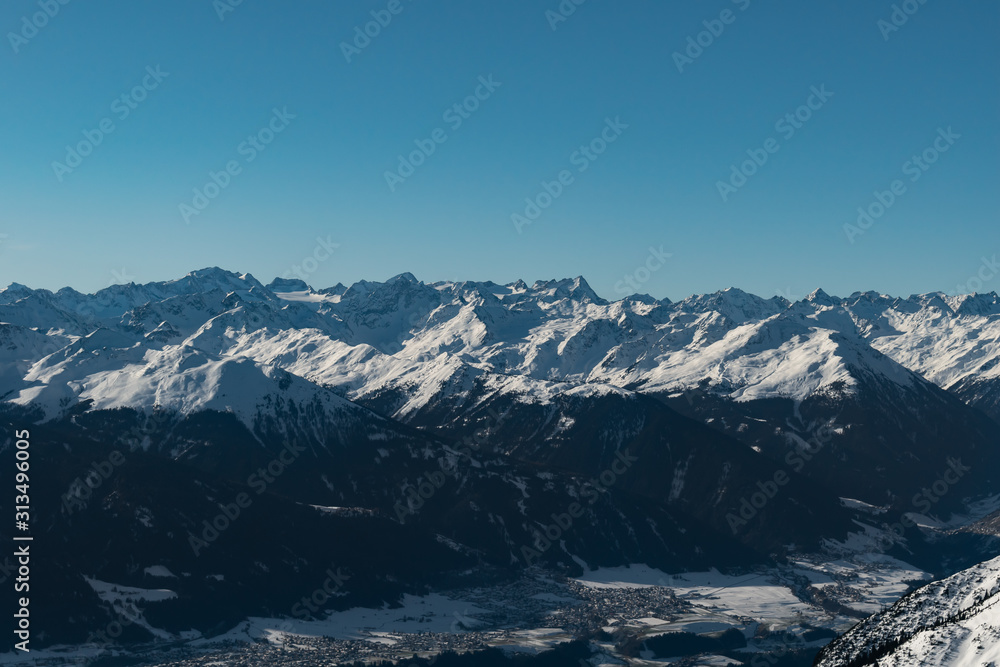 Snowy alpine mountain range on a clear sunny day during a winter morning