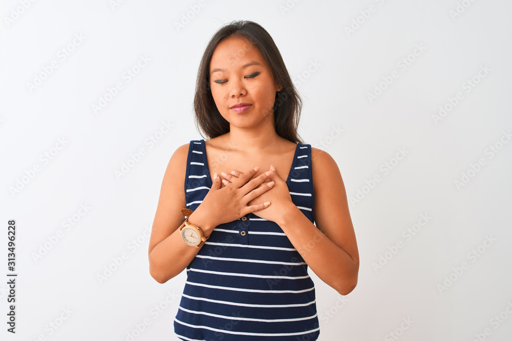 Young chinese woman wearing striped t-shirt standing over isolated white background smiling with hands on chest with closed eyes and grateful gesture on face. Health concept. Young chinese woman wearing striped t-shirt standing over isolated white background smiling with hands on chest with closed eyes and grateful gesture on face. Health concept.