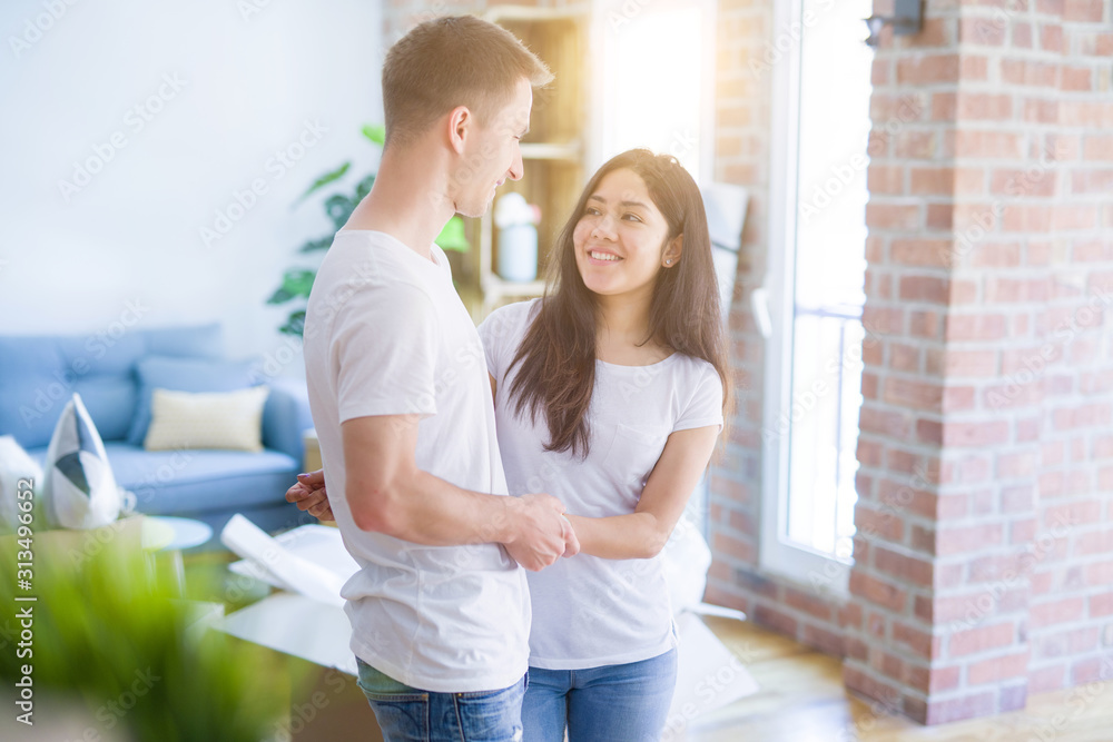 Young beautiful couple hugging at new home around cardboard boxes Young beautiful couple hugging at new home around cardboard boxes