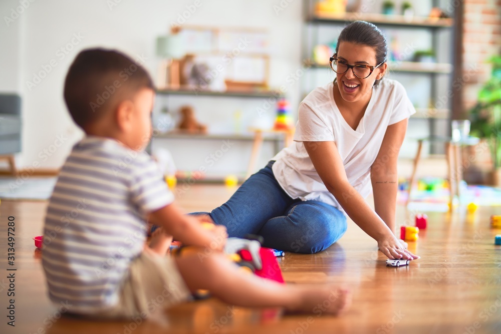 Beautiful teacher and toddler boy playing with tractor and cars at kindergarten Beautiful teacher and toddler boy playing with tractor and cars at kindergarten