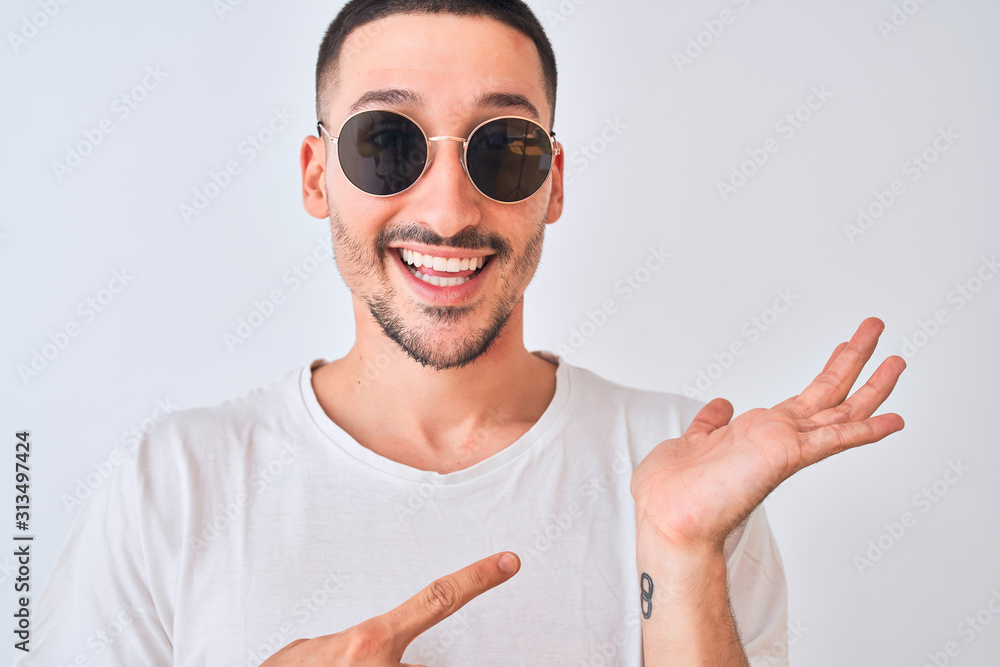 Young handsome man wearing sunglasses and casual t-shirt over isolated background very happy pointing with hand and finger Young handsome man wearing sunglasses and casual t-shirt over isolated background very happy pointing with hand and finger