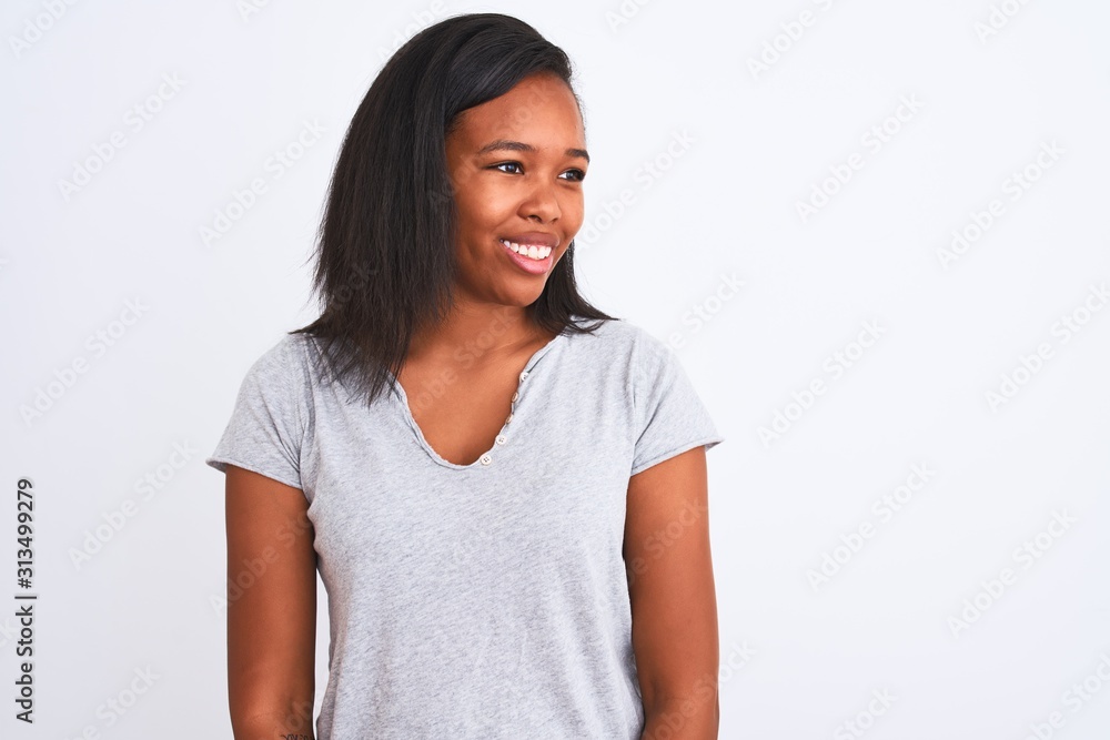 Beautiful young african american woman wearing casual t-shirt over isolated background looking away to side with smile on face, natural expression. Laughing confident. Beautiful young african american woman wearing casual t-shirt over isolated background looking away to side with smile on face, natural expression. Laughing confident.