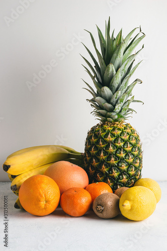 Assortment of tropical fruits  banana  kiwi  orange  tangerine  lemon  pineapple  grapefruit on textured white background