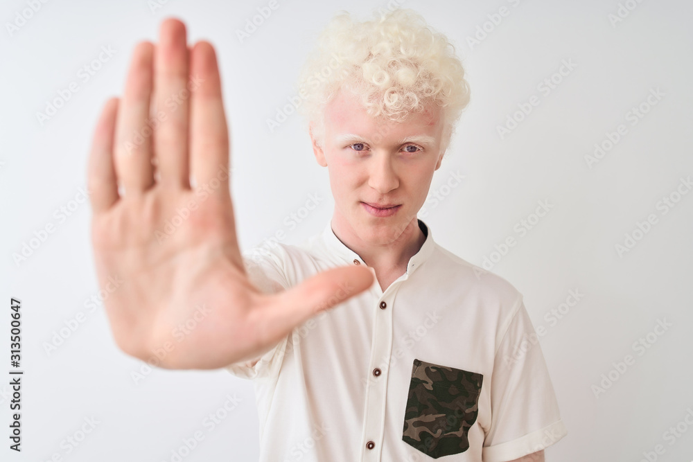 Young albino blond man wearing casual shirt standing over isolated white background with open hand doing stop sign with serious and confident expression, defense gesture Young albino blond man wearing casual shirt standing over isolated white background with open hand doing stop sign with serious and confident expression, defense gesture